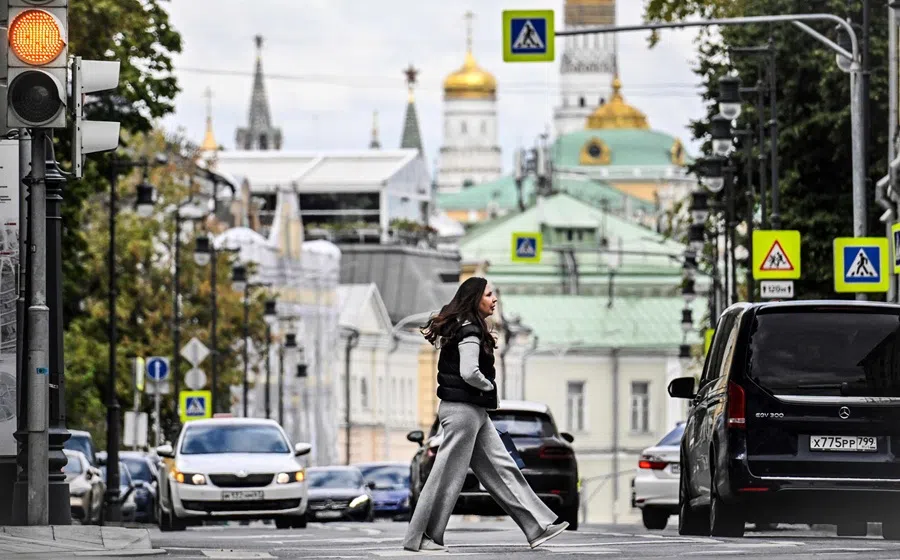 A woman crosses a street in central Moscow, with the Kremlin seen in distance, on 4 September 2025. (Alexander Nemenov/AFP)
