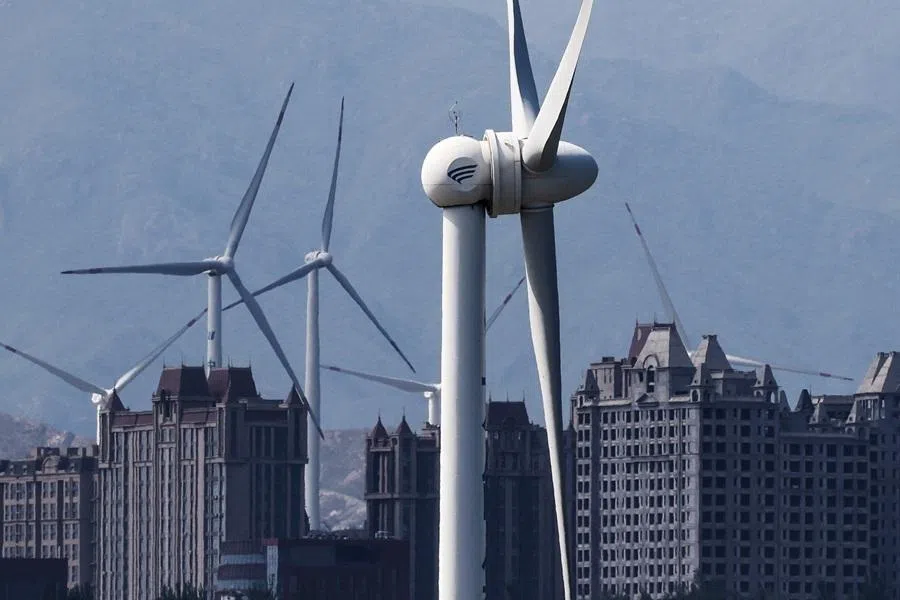 Wind turbines stand near a residential area with completed and unfinished apartment blocks in Zhangjiakou, Hebei province, China, 8 May 2026.