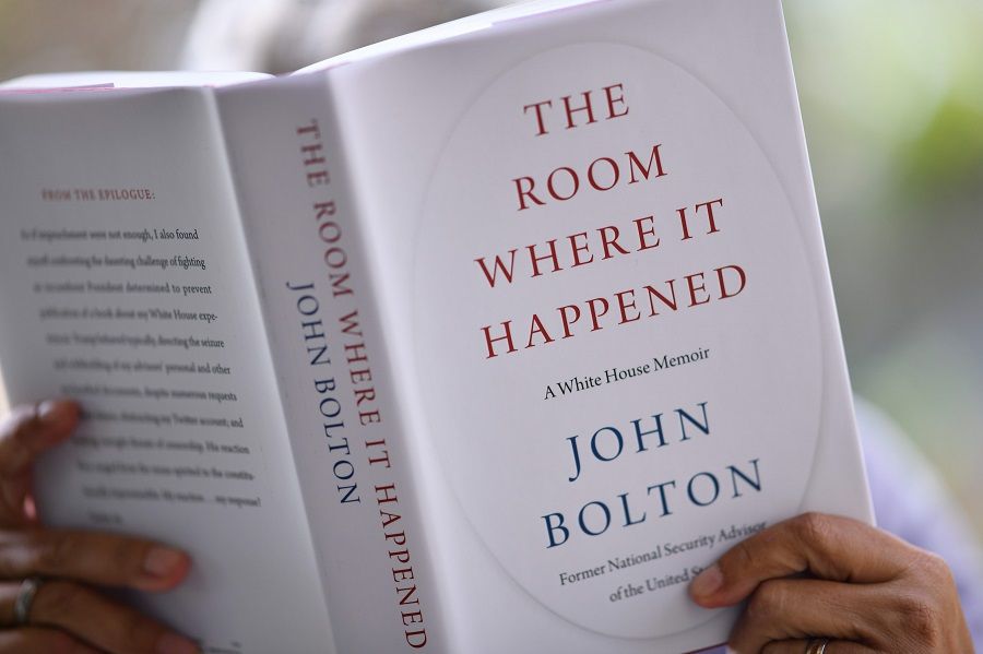 This illustration photo taken on 23 June 2020 shows a woman reading John Bolton's book The Room Where it Happened on the day of its release in Los Angeles. (Chris Delmas/AFP)