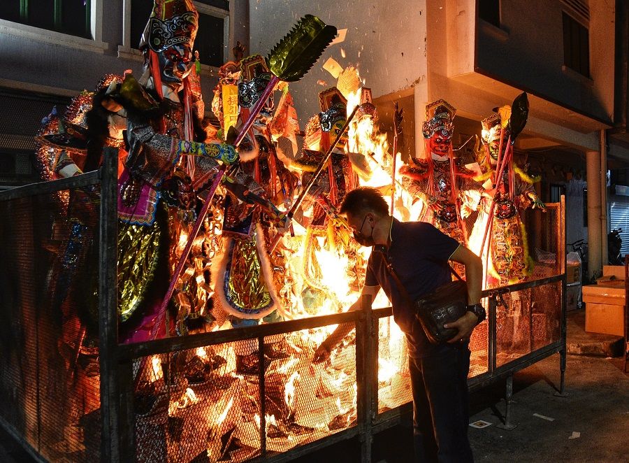 A man is seen burning life-sized paper figurines outside Fu Shan Tan, a religious organisation in Singapore, on 6 September 2021, on the last day of the Hungry Ghost Festival. (SPH)