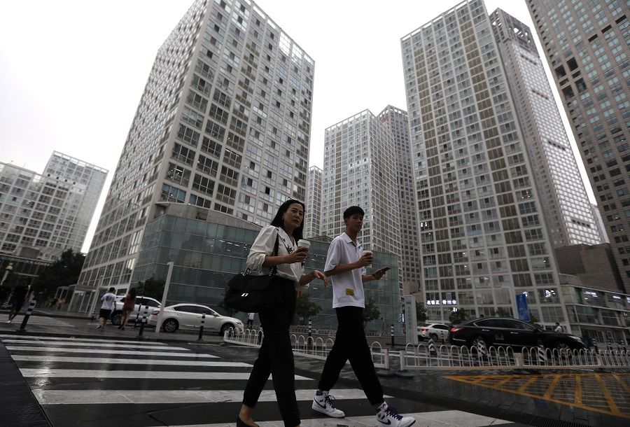 People walk past an office compound in Beijing's Central Business District, China, 13 July 2021. (Tingshu Wang/Reuters)