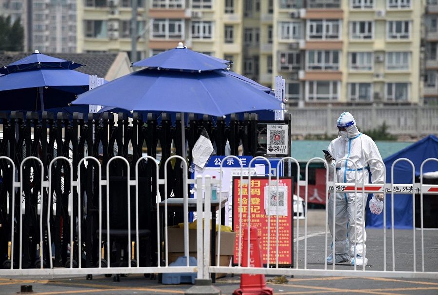 A security guard wearing personal protective equipment (PPE) stands at an entrance to a residential area under lockdown due to Covid-19 restrictions in Beijing, China, on 20 June 2022. (Noel Celis/AFP)