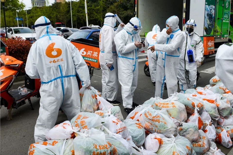 Delivery men wearing personal protective equipment prepare to deliver food bought online for residents who were restricted due to a recent Covid-19 outbreak, in Ningbo in China's eastern Zhejiang province on 2 April 2022. (AFP)