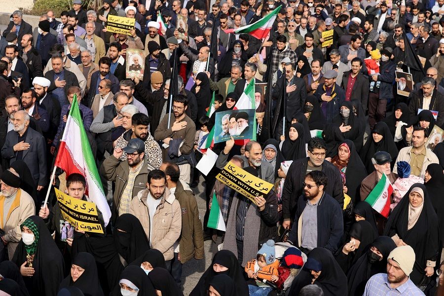 People wave flags and hold placards with anti-US and anti-Israel slogans on 5 January 2024 in Tehran, during the funeral of Faezeh Rahimi, one of the victims killed in the southen Iranian city of Kerman on 3 January in twin blasts during a commemmoration marking the anniversary of the killing of Major General Qasem Soleimani. (Atta Kenare/AFP)