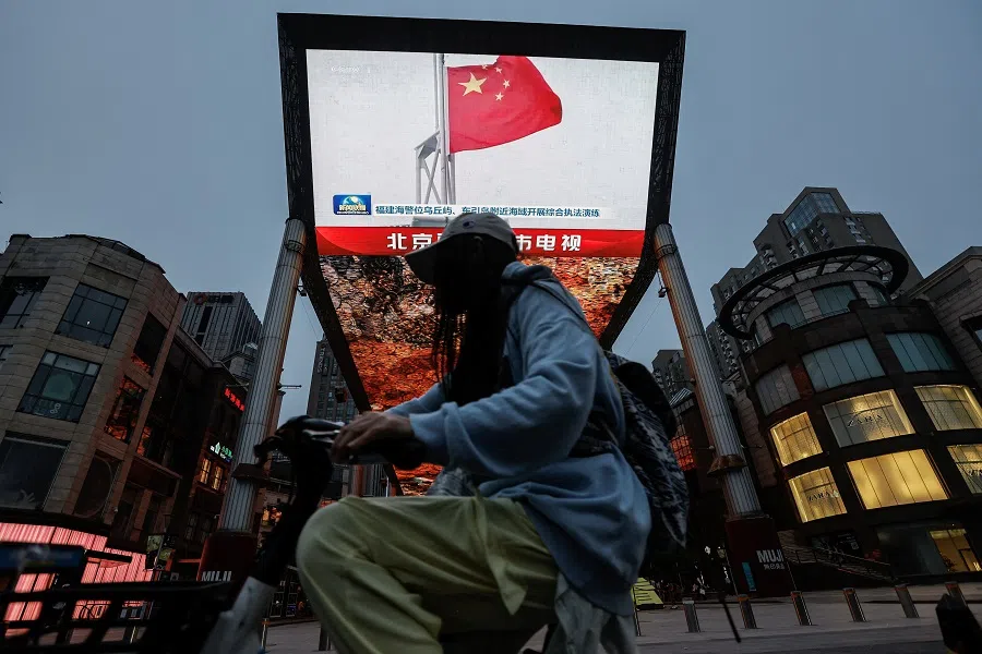 A person walks past a screen showing news footage of military drills conducted in areas around the island of Taiwan by the Eastern Theatre Command of the Chinese People’s Liberation Army (PLA), in Beijing, China, on 23 May 2024.