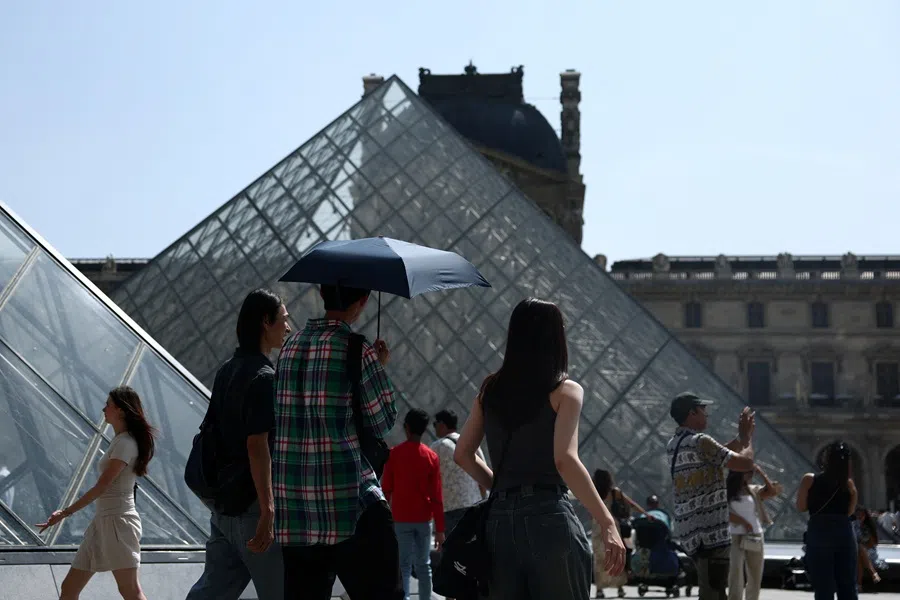 People walk in front of the Louvre Pyramid in Paris, France, on 13 June 2025. (Sarah Meyssonnier/Reuters)