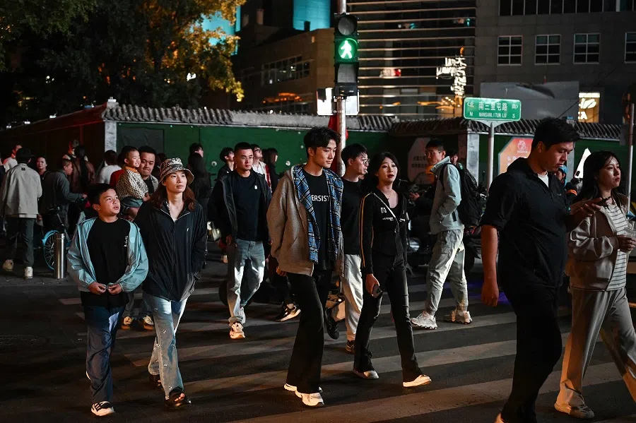 People cross a road outside a shopping mall on the third day of a week-long China’s National Day holidays in Beijing on 3 October 2024. (Greg Baker/AFP)