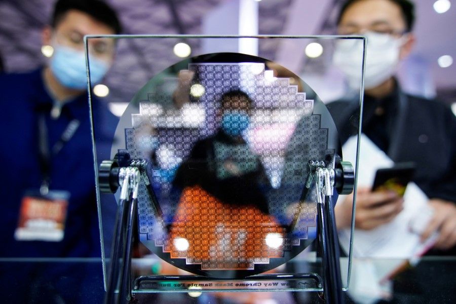 Visitors look at a display of a semiconductor device at Semicon China, a trade fair for semiconductor technology, in Shanghai, China, 17 March 2021. (Aly Song/Reuters)