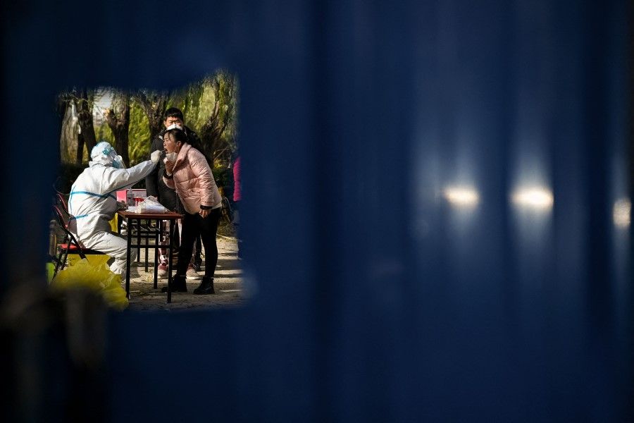 A health worker takes a swab sample from a woman at a residential area under lockdown due to Covid-19 coronavirus restrictions in Beijing on 25 November 2022. (Noel Celis/AFP)