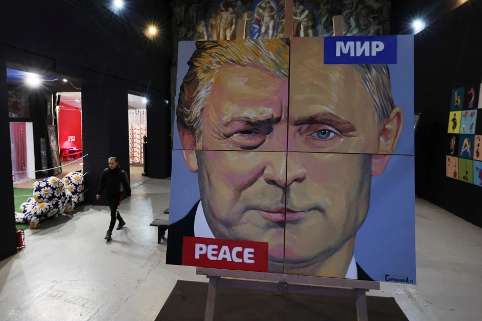 Artist Alexei Sergienko walks towards his painting “Peace to the World” showing a combination of faces of Russian President Vladimir Putin and US President Donald Trump, at the Sergienko gallery in Saint Petersburg, Russia, on 17 March 2025. (Anton Vaganov/Reuters)