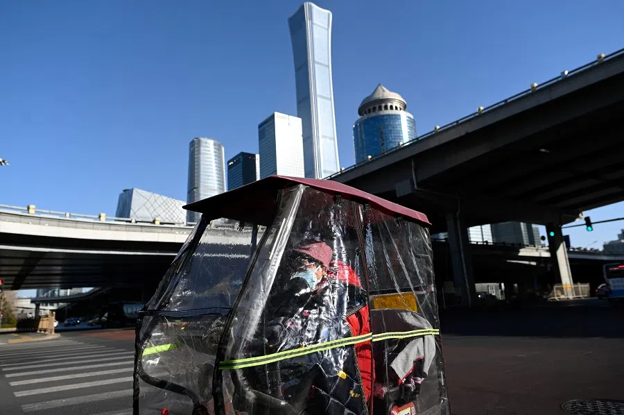 A woman rides her electric tricycle along a street in the central business district (CBD) of Beijing on 18 January 2021. (Wang Zhao/AFP)