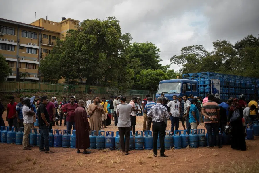 People stand next to their empty cylinders as they wait in a queue to buy domestic cooking gas, amid the country's economic crisis, in Colombo, Sri Lanka, 23 July 2022. (Adnan Abidi/Reuters)