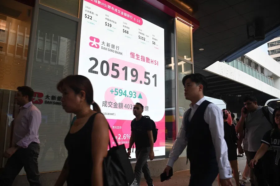 Pedestrians walk past a sign showing the numbers of the Hang Seng Index in Hong Kong on 27 September 2024. Hong Kong stocks soared more than 3% on 27 September, capping its best week since the global financial crisis, fuelled by a series of Chinese measures this week aimed at kickstarting the economy. (Peter Parks/AFP)