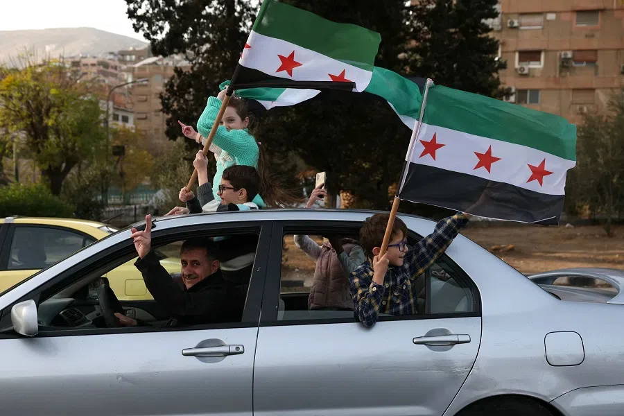 People celebrate with the Syrian opposition flag in Damascus on 10 December 2024, after Islamist-led rebels took Damascus in a lightning offensive on 8 December, ousting President Bashar al-Assad and ending five decades of Baath rule in Syria. (Omar Kadour/AFP)