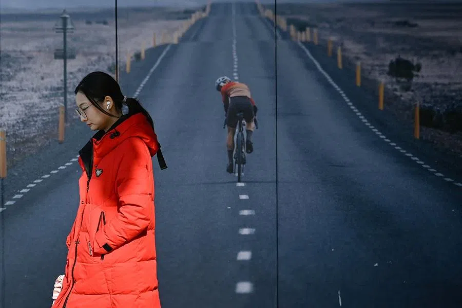 A woman walks past a poster outside a store in Beijing on 17 December 2025.