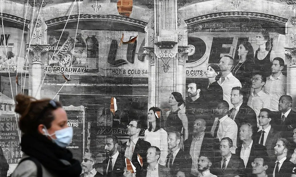 A person wearing a face mask walks past a mural by French photographer JR on 20 April 2020 in New York. (Angela Weiss/AFP)