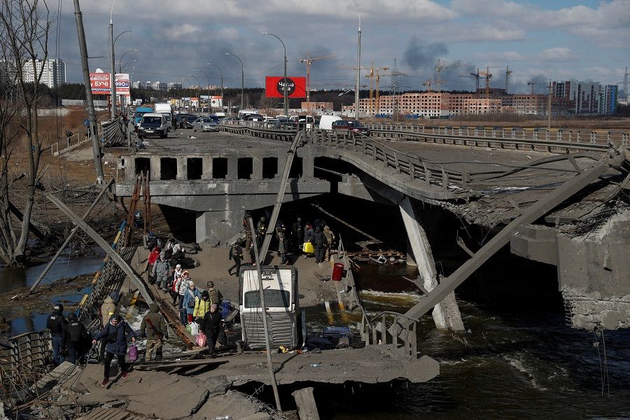 People cross the Irpin river next to a destroyed bridge as they evacuate from the Irpin town, as Russia's attack on Ukraine continues, outside of Kyiv, Ukraine, 10 March 2022. (Valentyn Ogirenko/Reuters)