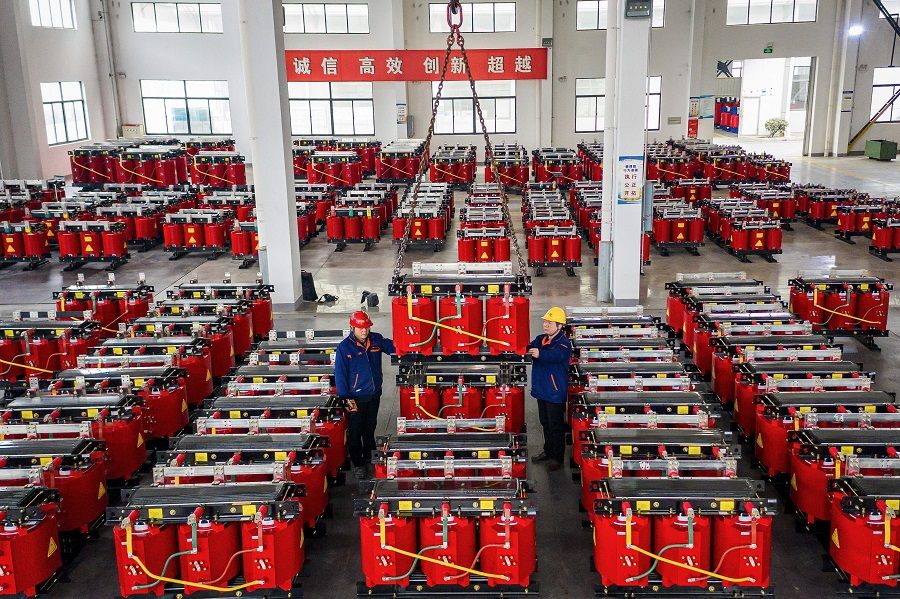 This photo taken on 4 January 2021 shows employees working on a dry-type transformer production line at an electrical production factory in Hai'an, Jiangsu province. China. (STR/AFP)