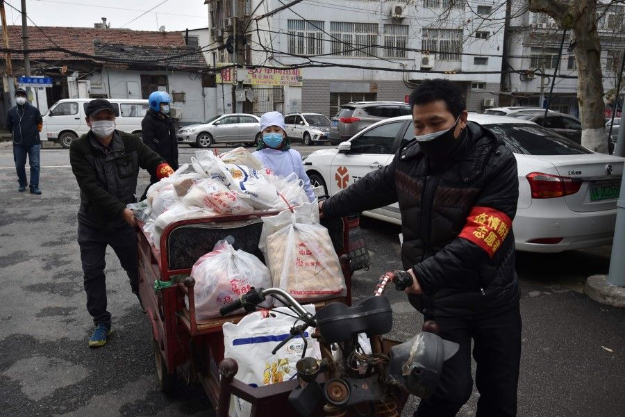 Volunteers deliver food and supplies to people quarantined at home in Wuhan. (STR/AFP)