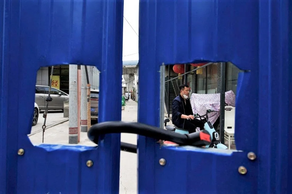 A man drives his bike inside a fenced residential area under a Covid-19 lockdown in Beijing, China, on 11 May 2022. (Noel Celis/AFP)