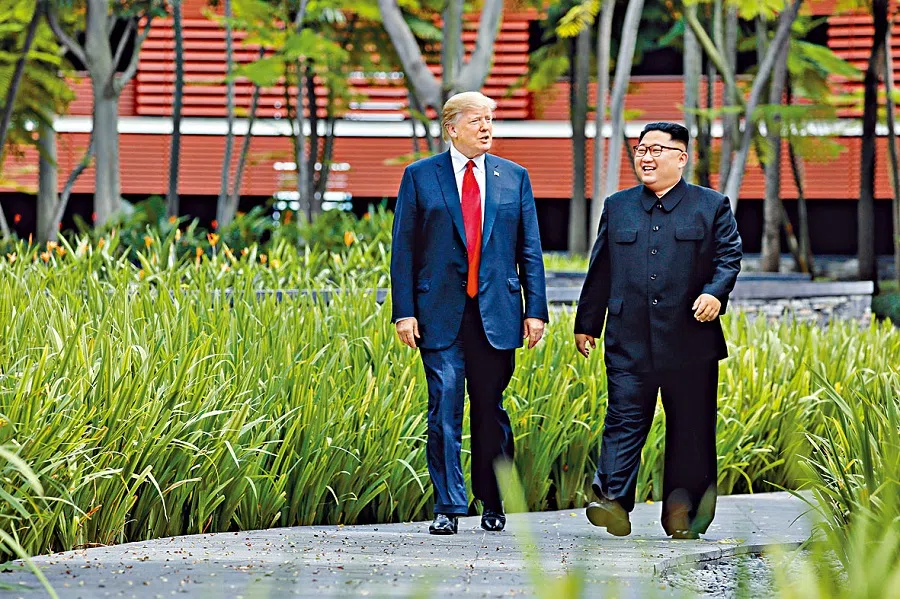 US President Donald Trump and North Korea’s leader Kim Jong Un walk together before their working lunch during their summit at the Capella Hotel on the resort island of Sentosa, Singapore, on 12 June 2018. (Jonathan Ernst/Reuters)