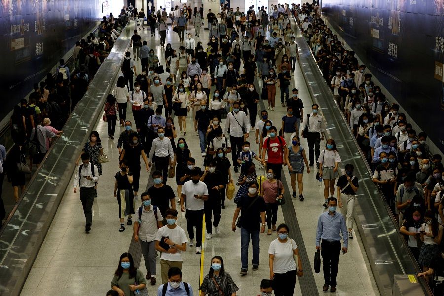 Passengers wearing protective masks walk through the Central Mass Transit Railway (MTR) station in Hong Kong, 17 August 2021. (Tyrone Siu/Reuters)