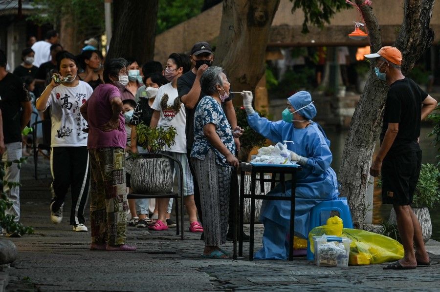A health worker takes a swab sample from a woman to test for Covid-19 next to a channel in the Zhujiajiao ancient water town in Shanghai, on 31 July 2022. (Hector Retamal/AFP)