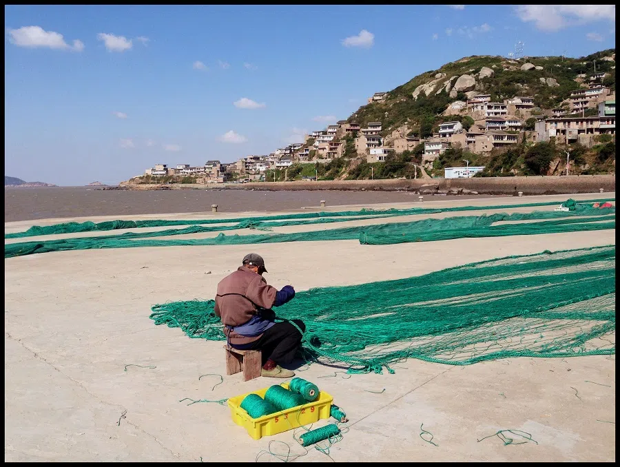 A fisherman mending large fishing nets in an island fishing community whose only means of subsistence is fishing, Huanglong Island off the coast of Shanghai.