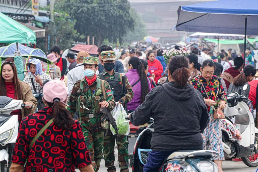 This photo taken on 10 November 2023 shows fighters of the ethnic rebel group Ta'ang National Liberation Army (TNLA) walking down a street market in the town of Namhkam in northern Shan state. A surprise offensive by Myanmar ethnic armed groups has blocked two strategically vital roads to the country's biggest trading partner China, choking cross-border commerce and denying the cash-strapped junta taxes and foreign exchange. (Mai Nyi/AFP)