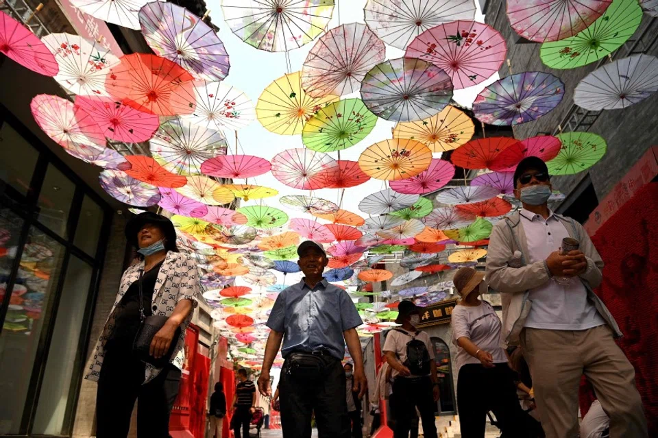 People walk along Qianmen street in Beijing on 19 May 2021. (Noel Celis/AFP)