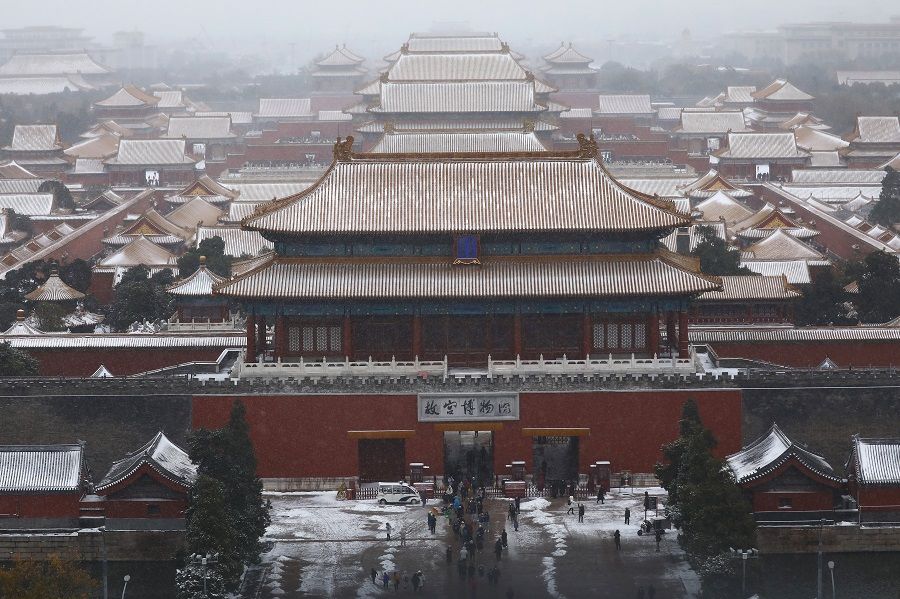 Tourists are seen at an entrance of the Forbidden City amid snowfall, in Beijing, China, 7 November 2021. (Tingshu Wang/Reuters)