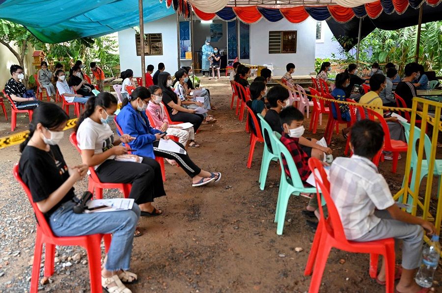 Youths wait to receive the Sinovac Covid-19 coronavirus vaccine at a health centre in Phnom Penh, Cambodia, on 29 August 2021. (Tang Chhin Sothy/Pool/AFP)