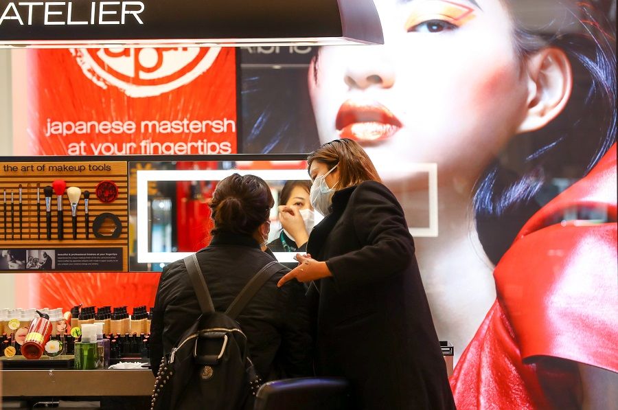 In this photo taken on 30 March, a sales assistant helps a consumer try-on makeup products, as shopping malls in Wuhan are gradually reopening. (CNS)
