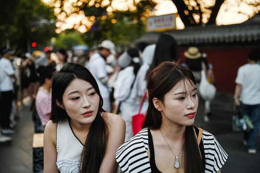 Women rest outside the Drum Tower during sunset in Beijing on 22 July 2025. (Greg Baker/AFP)