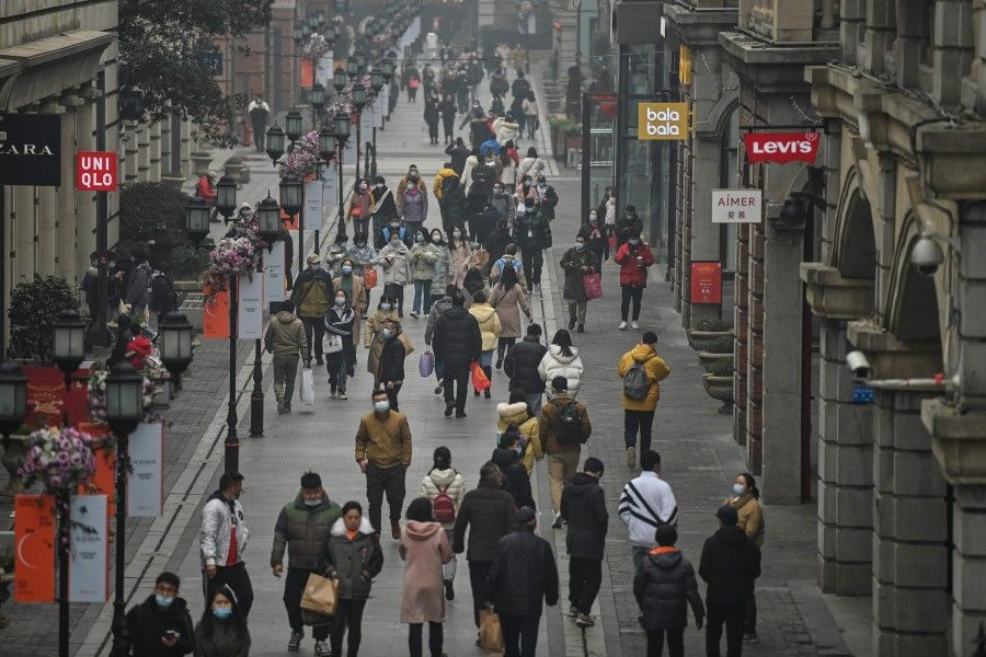 People walk along a pedestrian street in Wuhan, China's central Hubei province on 23 January 2021, one year after the city went into lockdown to curb the spread of the Covid-19 coronavirus. (Photo by Hector RETAMAL / AFP)