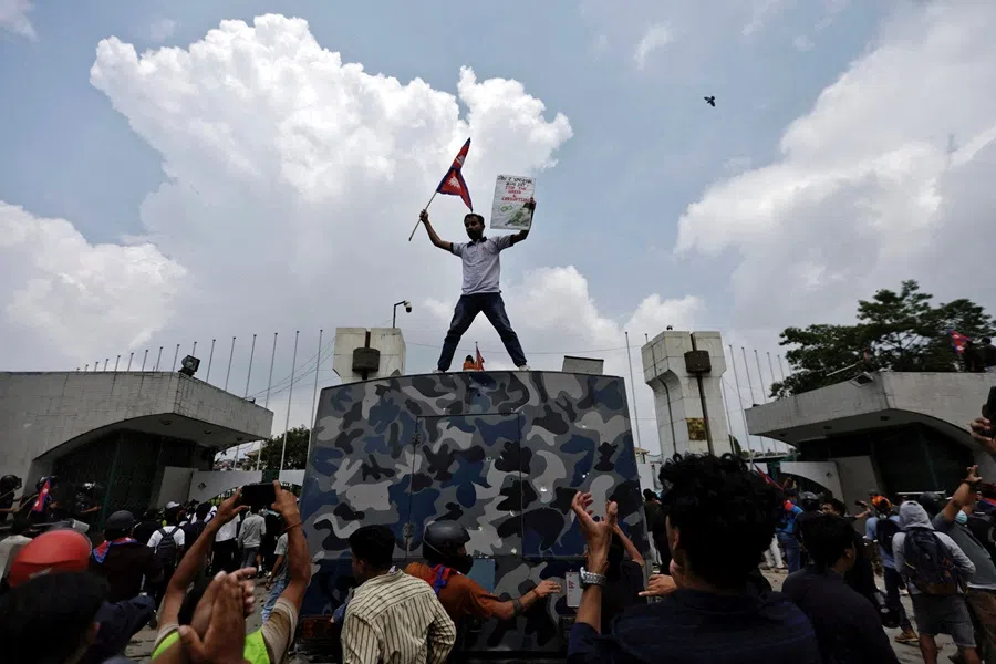 A demonstrator waves a flag as he stands atop a vehicle near the entrance of the Parliament during a protest against corruption and government’s decision to block several social media platforms, in Kathmandu, Nepal, on 8 September 2025.