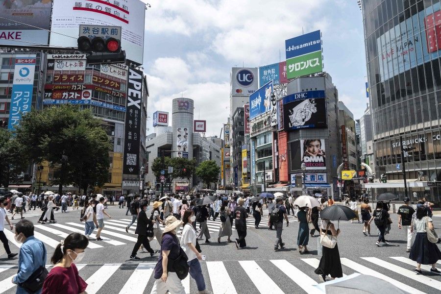 People cross a street in Tokyo on 12 July 2021. (Charly Triballeau/AFP)