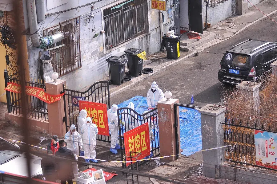 Staff members wearing personal protective equipment stand at the entrance to a residential area, which is restricted due to a recent outbreak of Covid-19, in Harbin, Heilongjiang province, China, on 15 March 2022. (AFP)