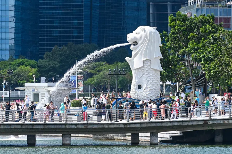 People gather for photograph next to the Merlion statue at Marina Bay waterfront in Singapore on 18 March 2024. (Roslan Rahman/AFP)