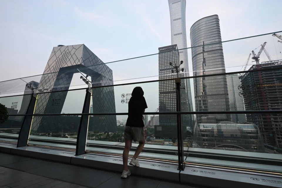 A woman looks at buildings on the the skyline from a viewing platform in a mall in Beijing’s central business district on 11 July 2024. (Greg Baker/AFP)