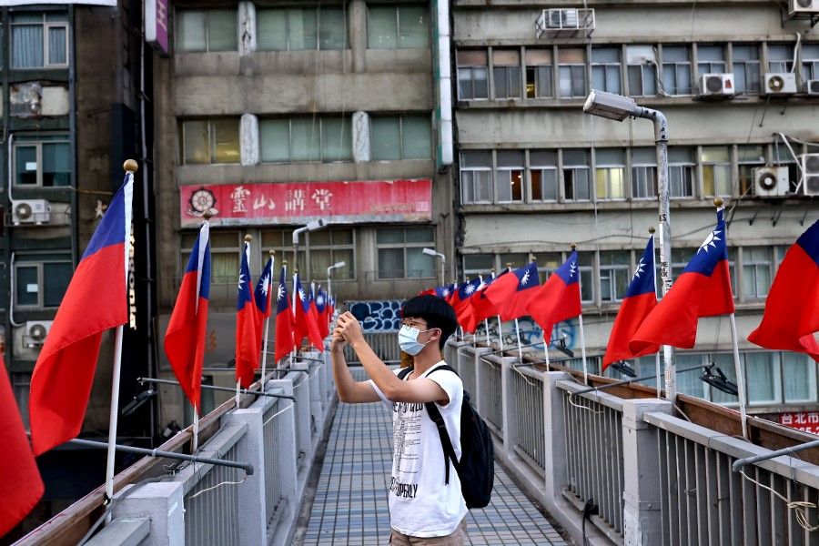A man takes photos on an overpass decorated with Taiwan flags in Taipei, Taiwan, 7 October 2021. (Ann Wang/Reuters)