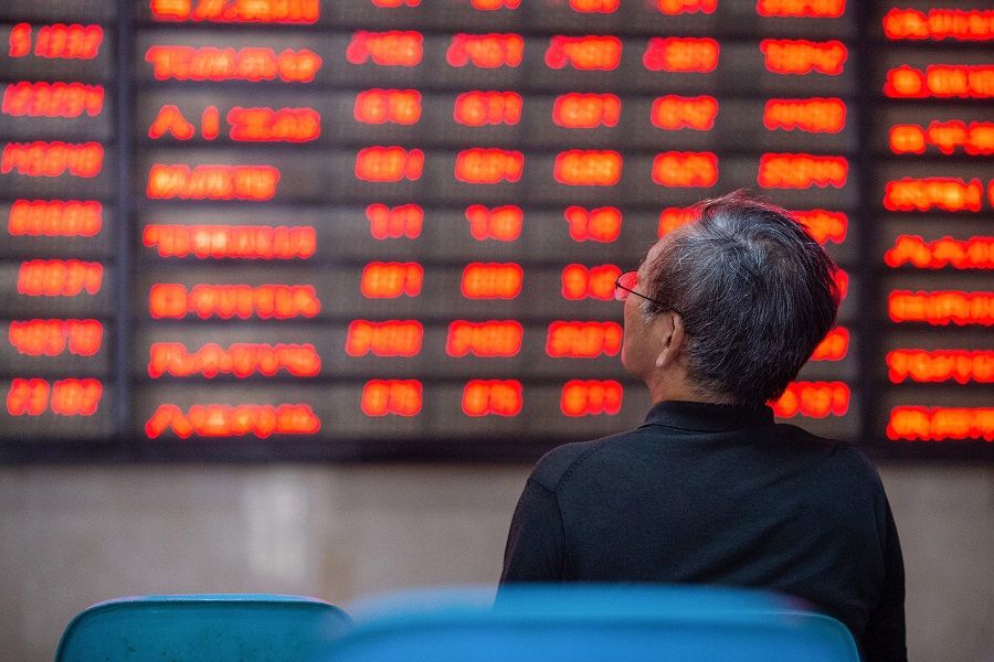 An investor looks at screens showing stock market movements at a securities company in Nanjing, China, on 6 July 2020. (STR/AFP)