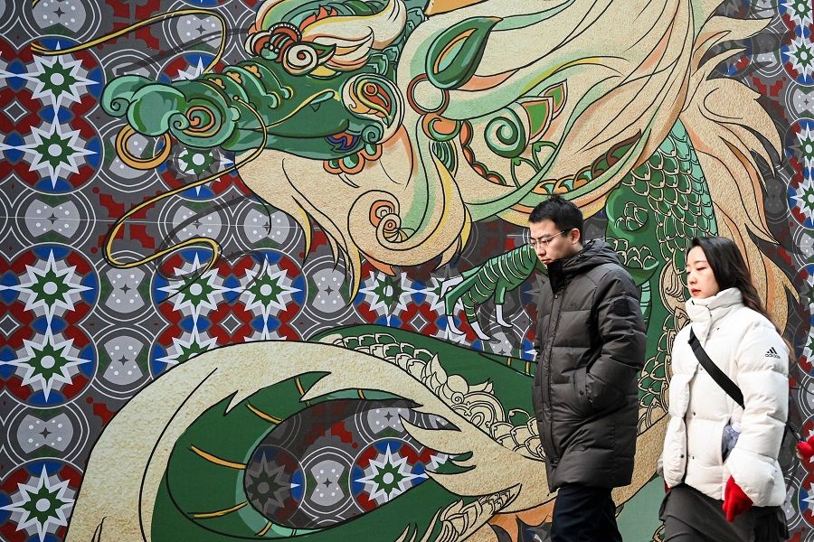 People walk past a mural of a dragon in Beijing, China, on 30 December 2023. (Jade Gao/AFP)