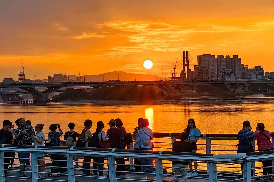People watch the sunset at Dadaocheng Wharf along Tamsui River, Taiwan, on 11 December 2023. (CNS)