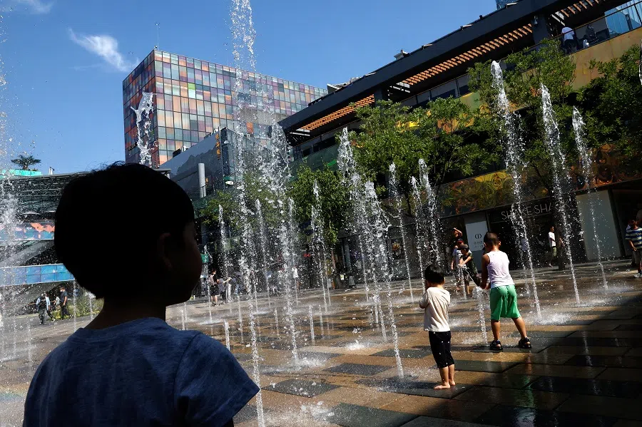 Children cool off in a water fountain amid an orange alert for heatwave, at a shopping area in Beijing, China, 22 June 2023. (Tingshu Wang/Reuters)