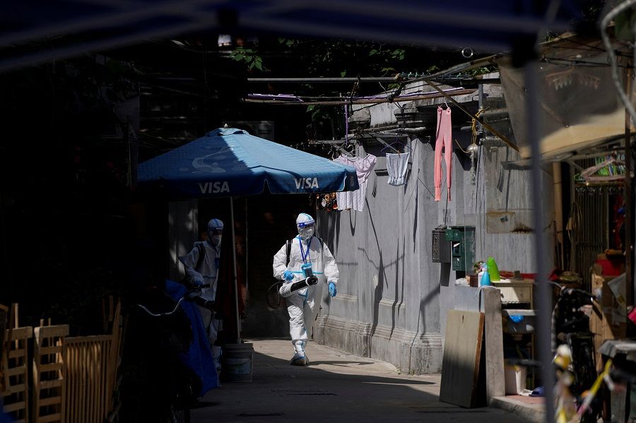 Workers in protective suits disinfect a closed residential area during lockdown, amid the Covid-19 outbreak, in Shanghai, China, 18 May 2022. (Aly Song/Reuters)