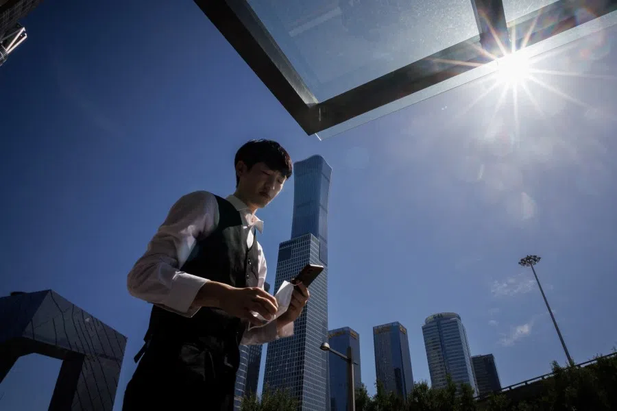 A man walks in front of the skyline of the Central Business district in Beijing, China, 14 July 2022. (Thomas Peter/Reuters)