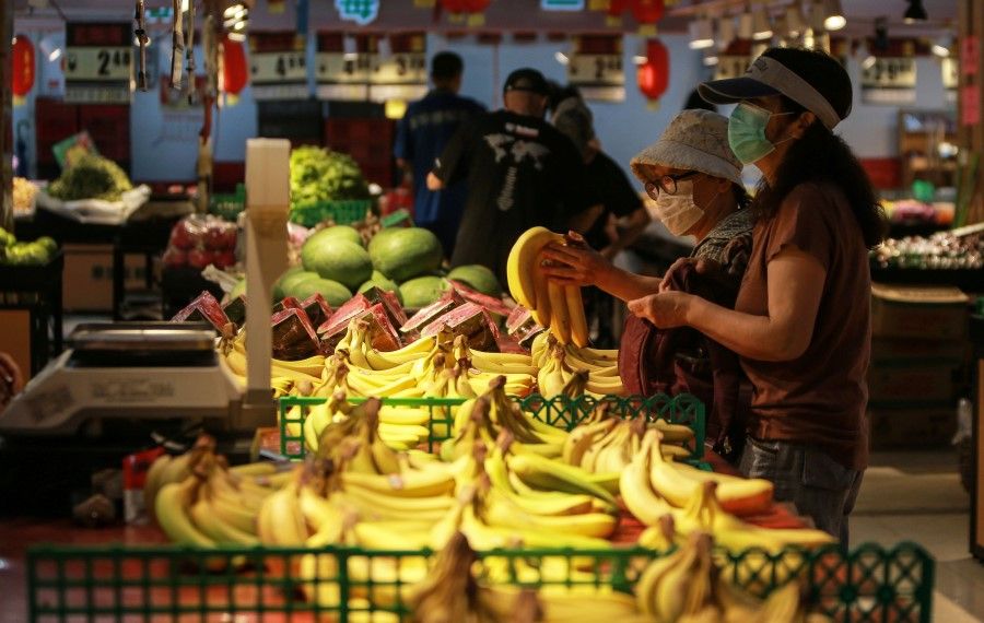 Customers buy bananas at a market in Shenyang, in China's northeastern Liaoning province on 10 August 2020. (STR/AFP)