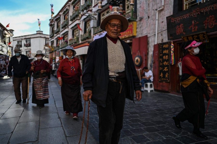 This photograph taken during a government organised media tour shows pilgrims praying while walking around the Jokhang Temple in the regional capital Lhasa, in China's Tibet Autonomous Region on 1 June 2021 (Hector Retamal/AFP)