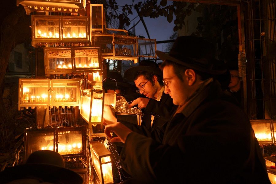 Ultra-Orthodox Jews light candles on the eighth and final night of the Jewish holiday of Hanukkah, the Jewish Festival of Lights, in Jerusalem, Israel, on 5 December 2021. (Menahem Kahana/AFP)